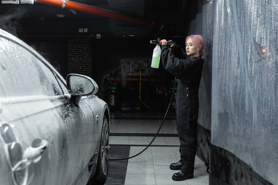 A young woman uses a power spray to clean a car wi