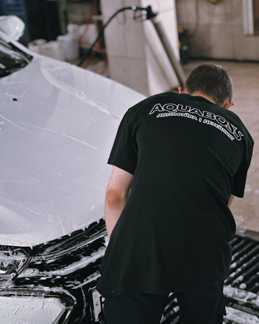 Professional cleaning a white car with foam in an
