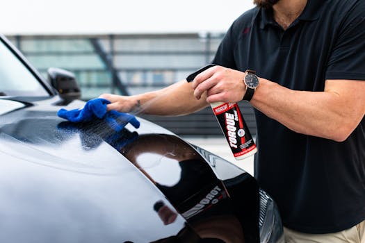 A man cleaning a black car hood with a spray and m