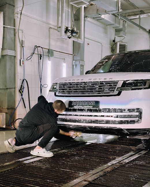 A worker cleaning a Range Rover in an indoor car w