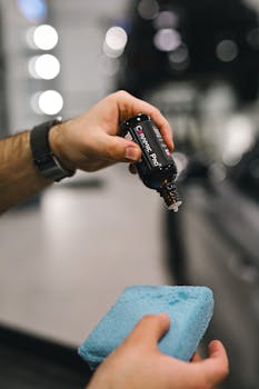 Hands applying car detailing liquid with a blue sp