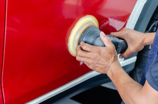 Close up of a worker buffing red car paint for shi
