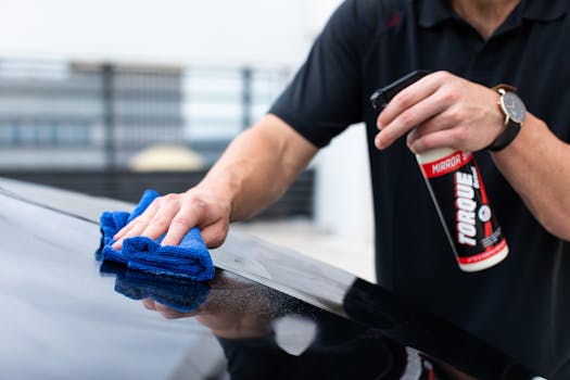 Hands cleaning car with microfiber cloth and spray