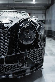 Close up of a sleek black luxury car with soapy fo