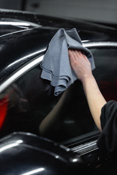 Hand cleaning black car exterior with cloth showca